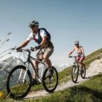 two men are cycling in the mountains