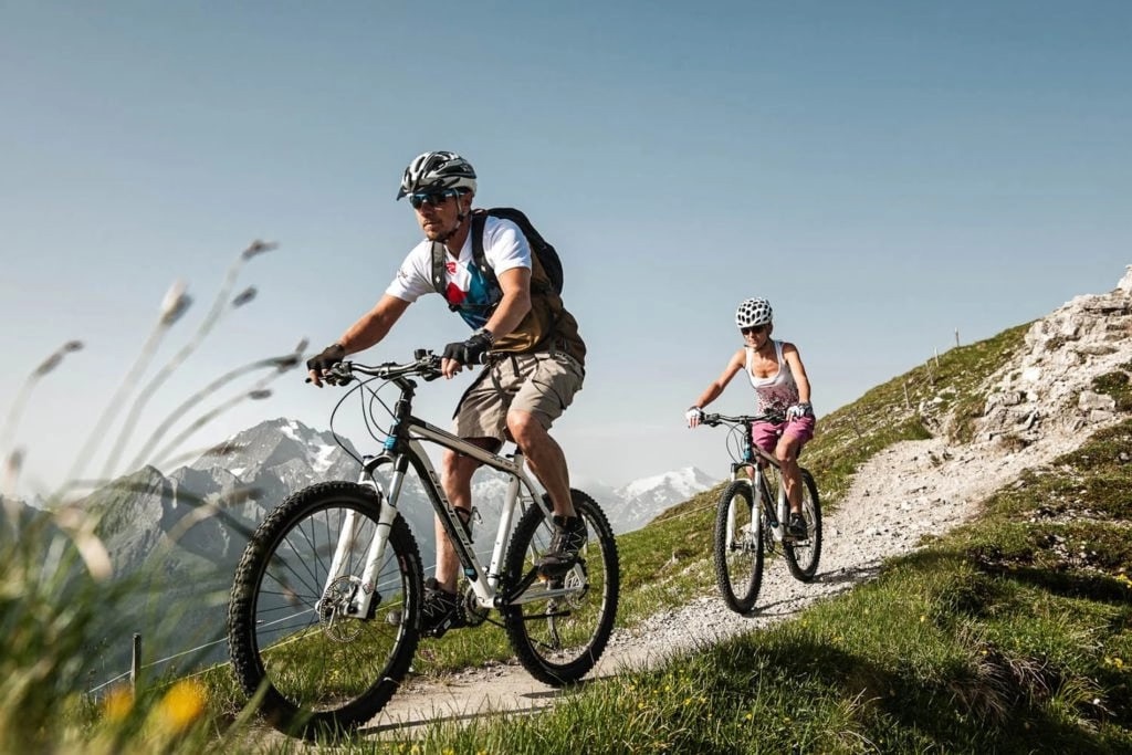 two men are cycling in the mountains